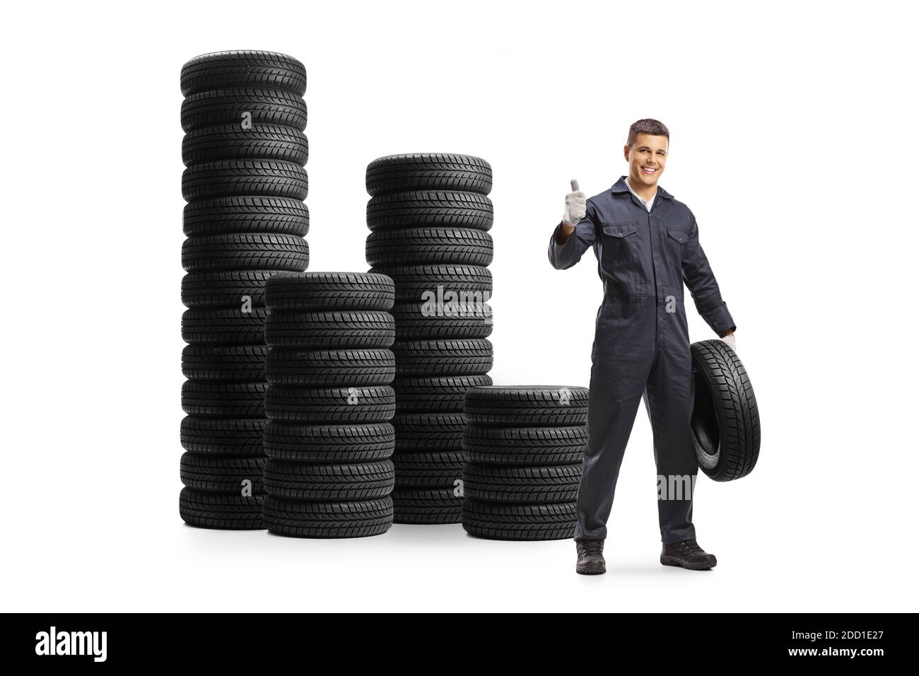 Auto mechanic with a car tire and piles of tires behind isolated on white background Stock Photo