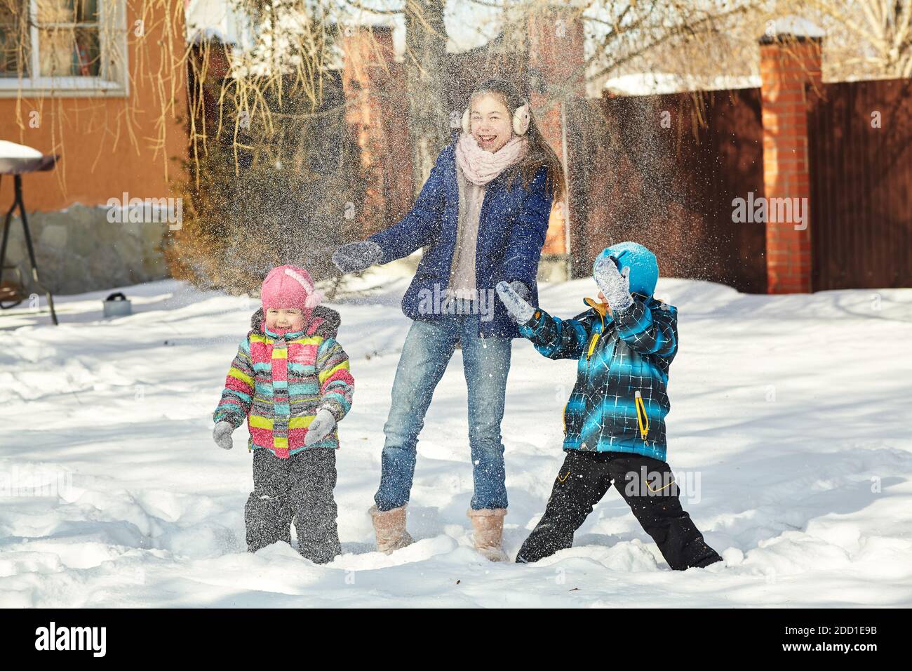 happy children playing with snow in the yard of his house in the winter ...