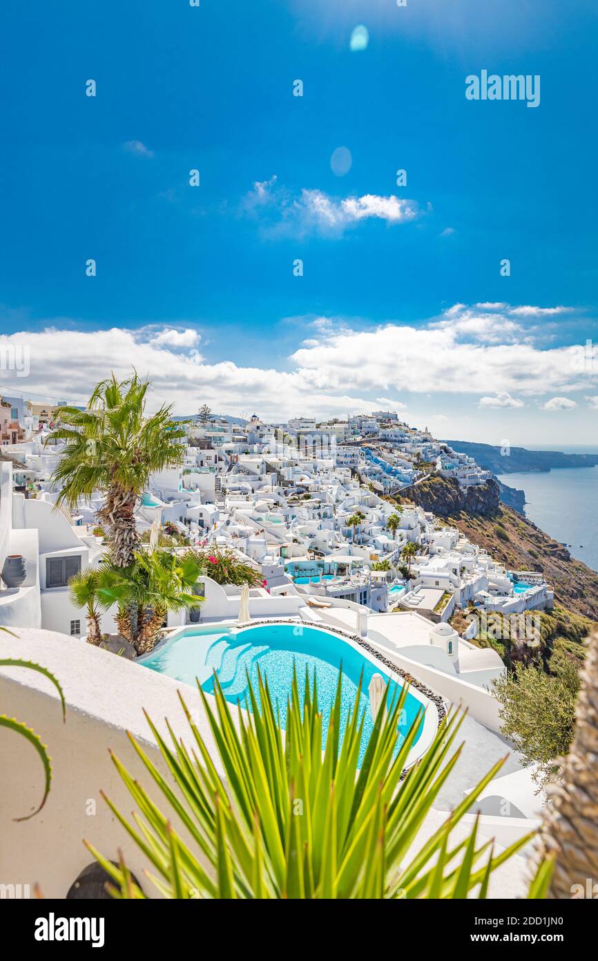 View of caldera and swimming pool in foreground, typical white architecture village on Santorini island, Greece. Summer vacations background. Luxury Stock Photo