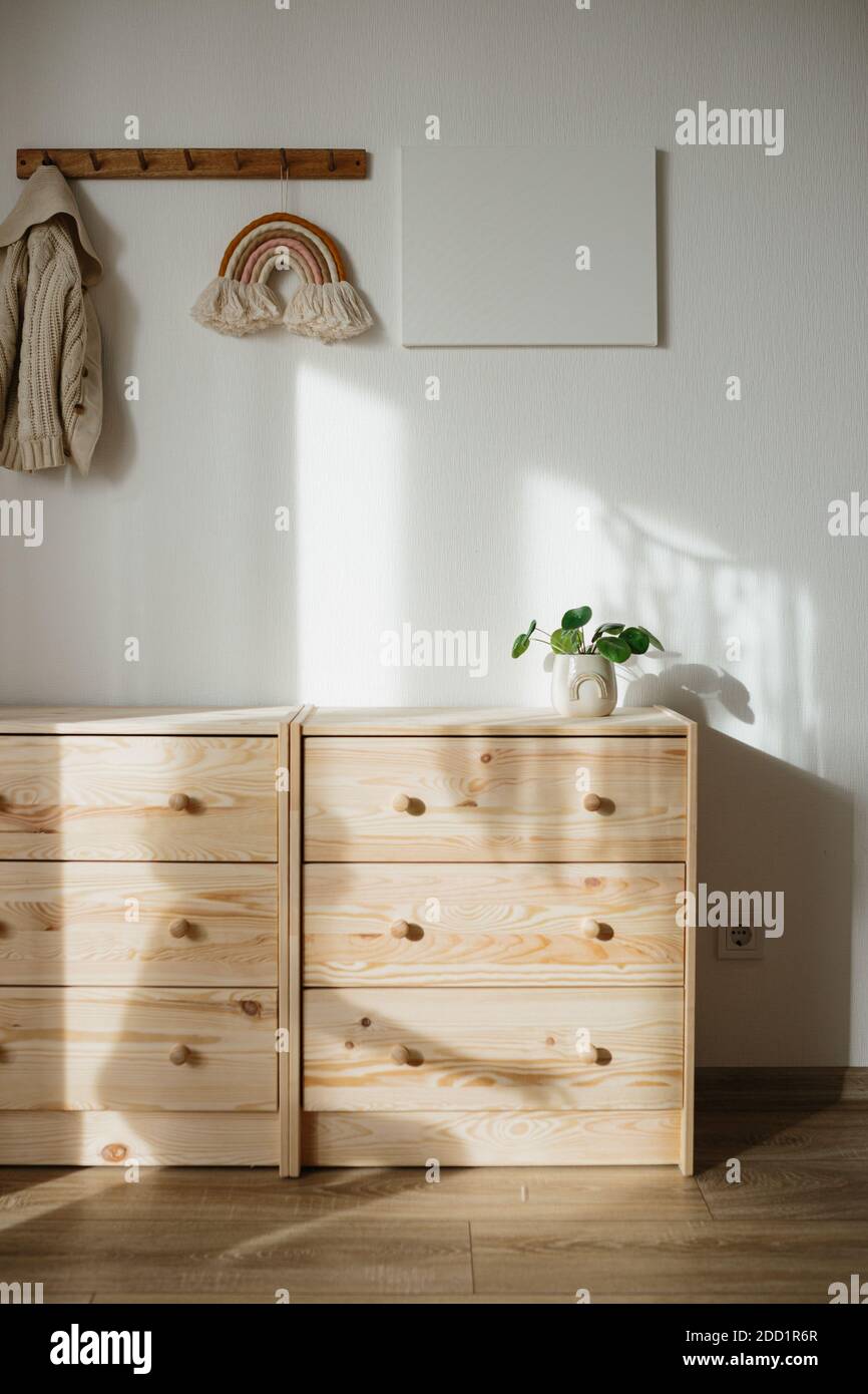 Wooden chest of drawers, pilea or Chinese money plant, rainbow wall hanging decor, canvas mock up, eco friendly children room concept, child shadow Stock Photo