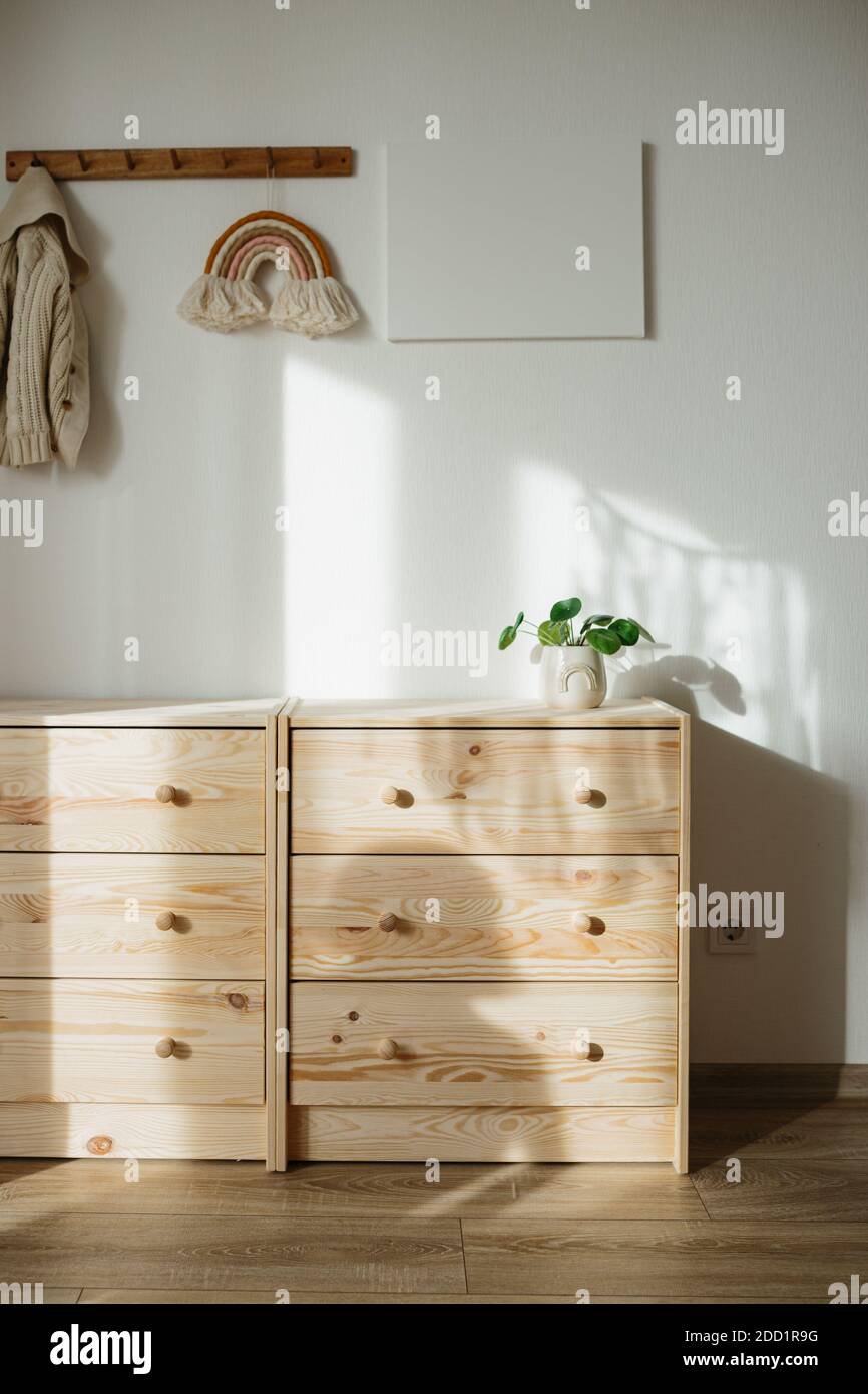 Wooden chest of drawers, pilea or Chinese money plant, rainbow wall hanging decor, canvas mock up, eco friendly children room concept, child shadow Stock Photo
