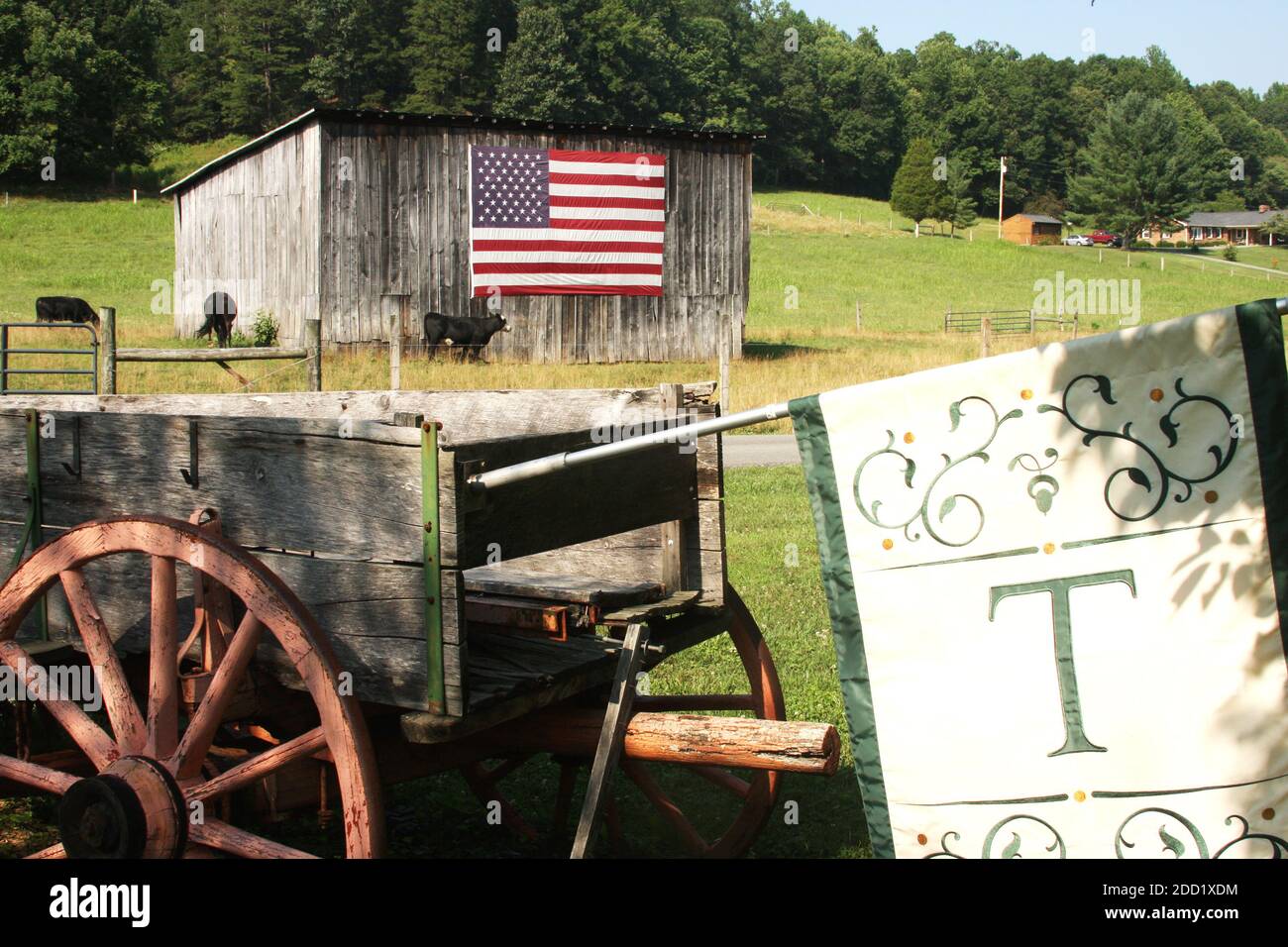 Virginia, USA. American flag displayed on an wooden shed. Old cart with flag used as yard decor. Stock Photo