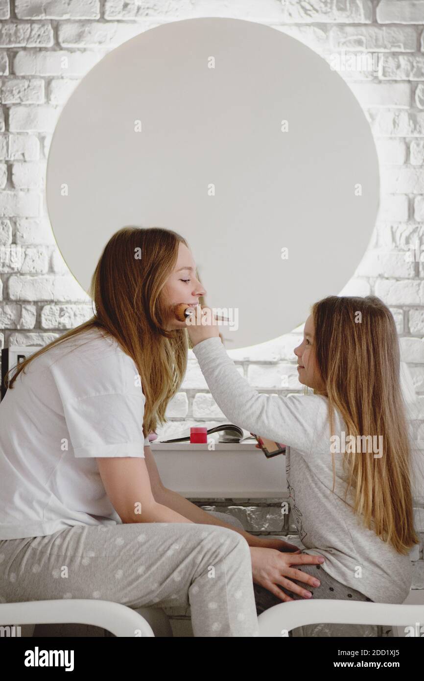 Close up portrait of little girl doing makeup to her beautiful mom. Stock Photo