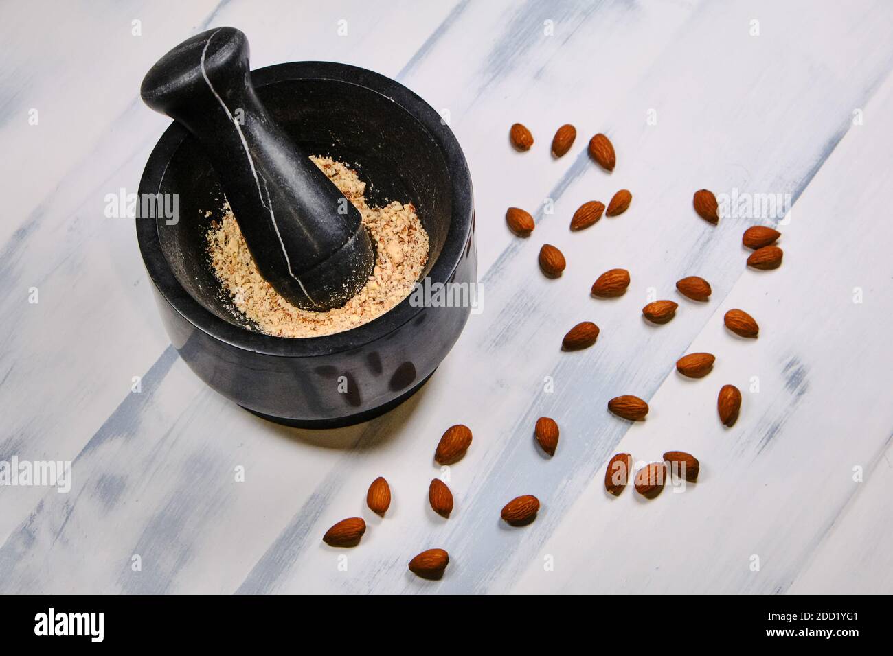 Almonds for cooking on a wooden white background. Grinding nuts in a