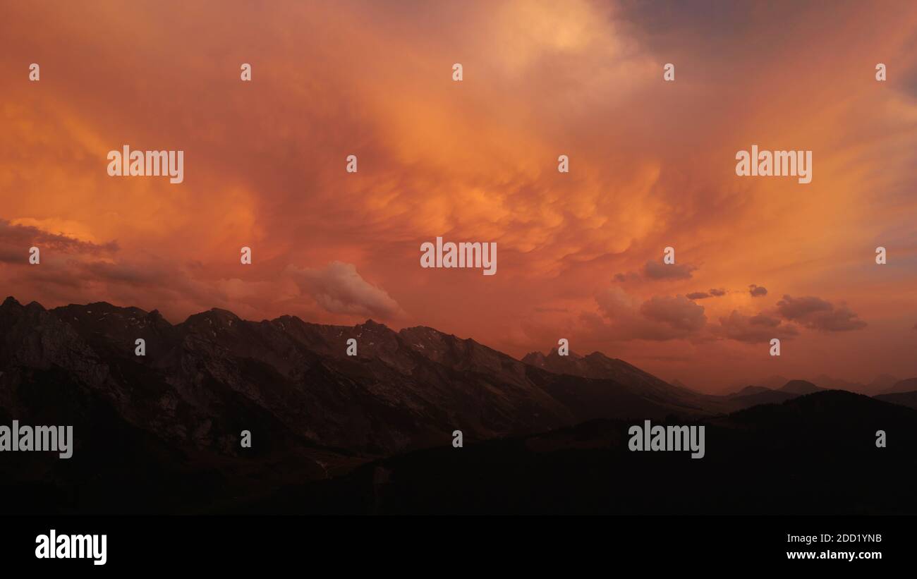 A red/orange stormy sky over the Aravis Range at sunset. Stock Photo