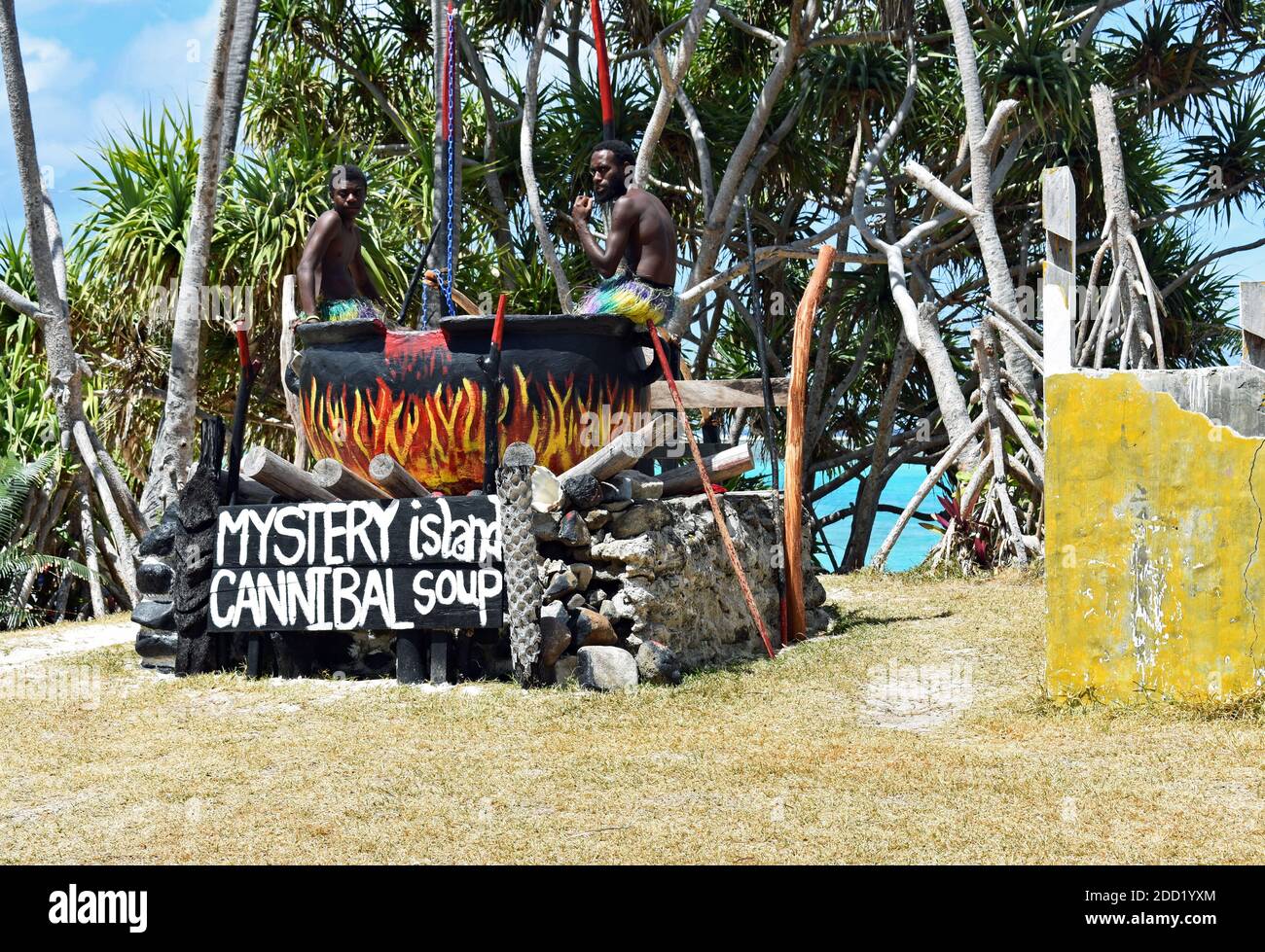 Locals pose for pictures in a huge black pot with painted flames for cannibal soup on Mystery Island, a popular cruise stop in Vanuatu, South Pacific. Stock Photo