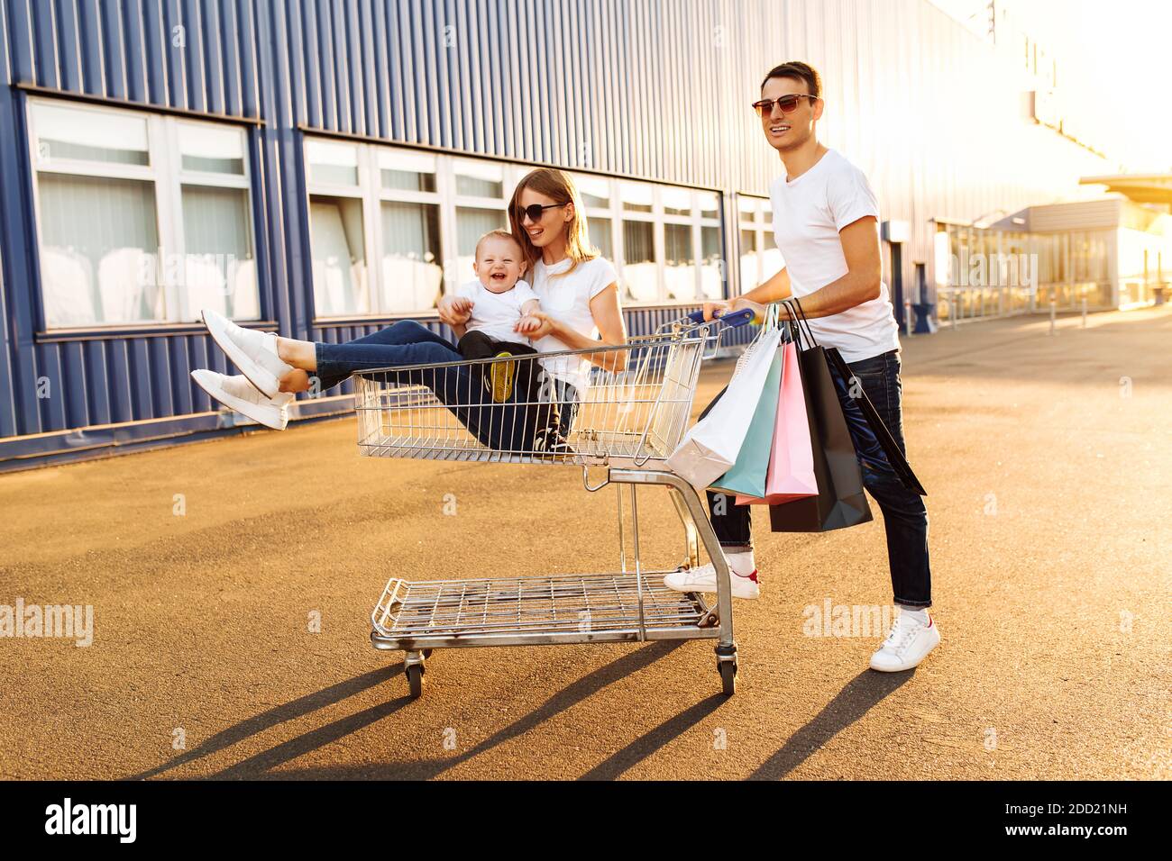 happy family, with shopping bags having fun riding on shopping cart ...