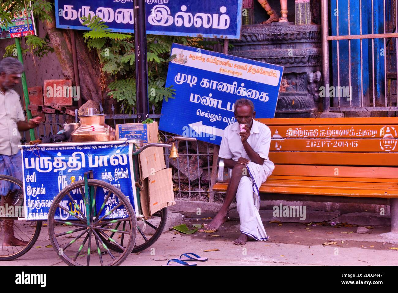 Madurai, India - November 02, 2018: A man sitting on a bench drinking tea in front of hindu temple named Thiruparankundram Murugan or Subramanya Swamy Stock Photo
