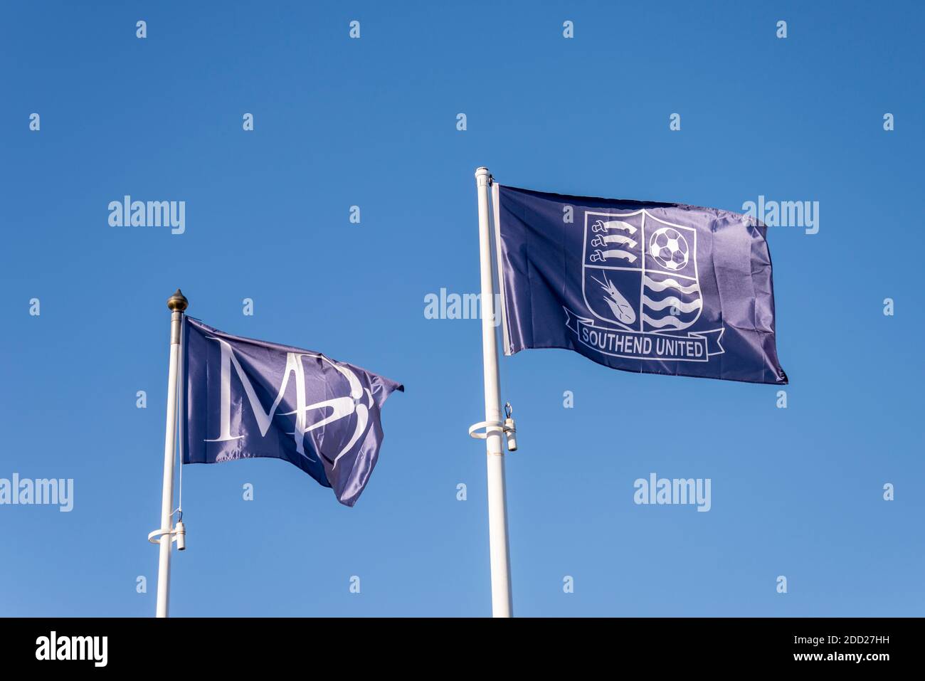 Southend United Football Club and Martin Dawn flags flying in blue sky outside Roots Hall, Southend on Sea, Essex, UK. New flags on pole Stock Photo