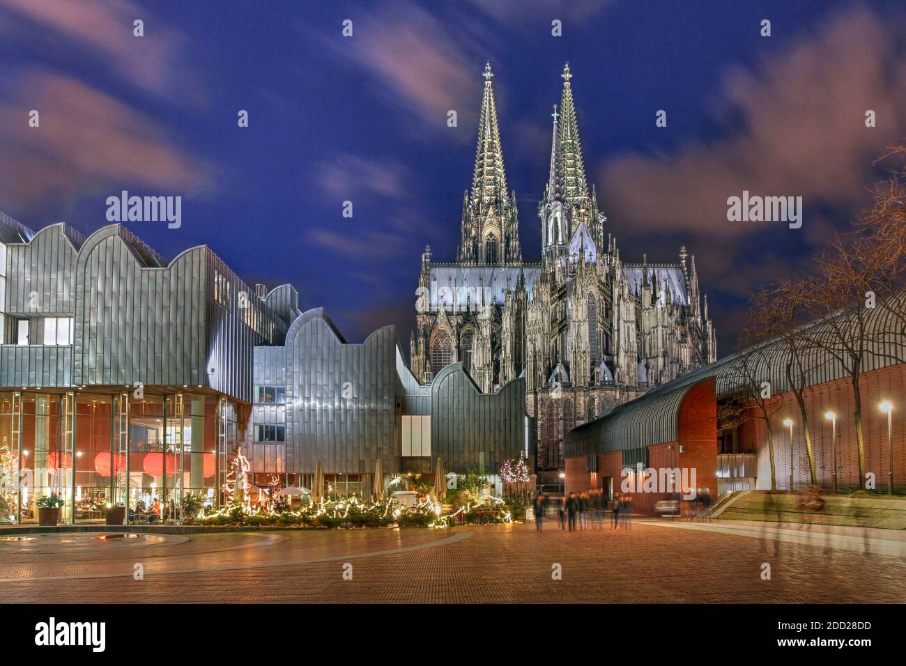Night scene of Heinrich-Boell square in Cologne, Germany with the Cologne Philarmonie Hall and the Ludwig Museum, overlooked by the majestic Cologne C Stock Photo