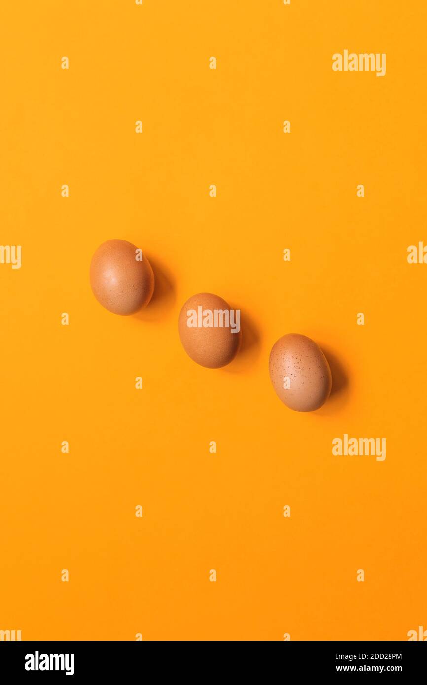 minimalist three eggs on orange background Stock Photo