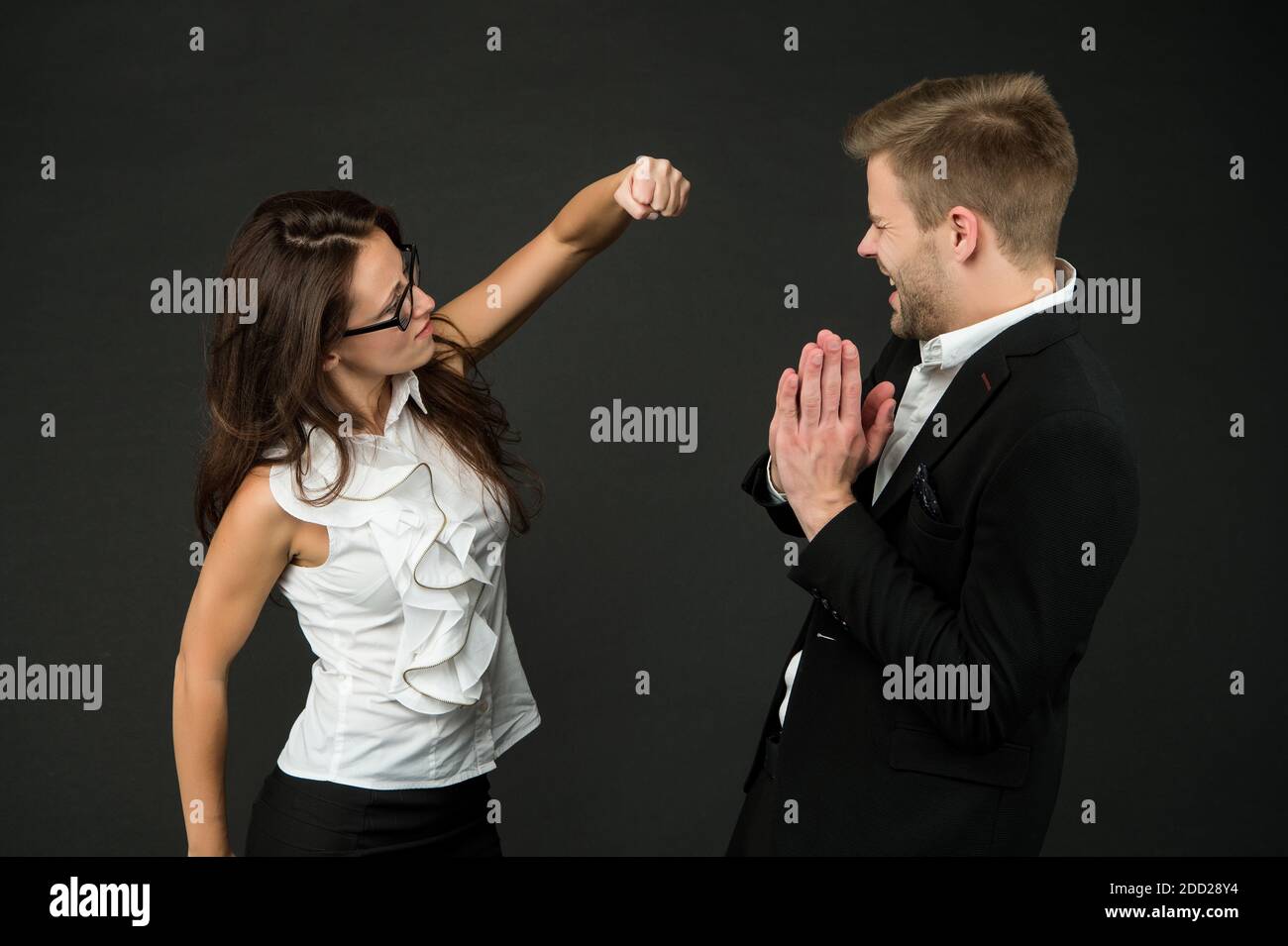 Confrontation by force. Angry woman throw punch at male colleague