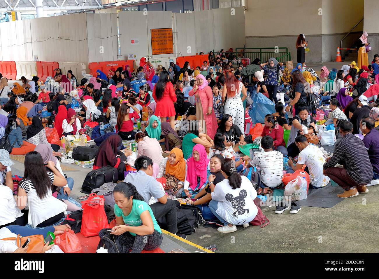 SINGAPORE - November 25, 2018: Foreign domestic workers gathering at a vacant plot of land underneath a train station on a Sunday afternoon. Stock Photo
