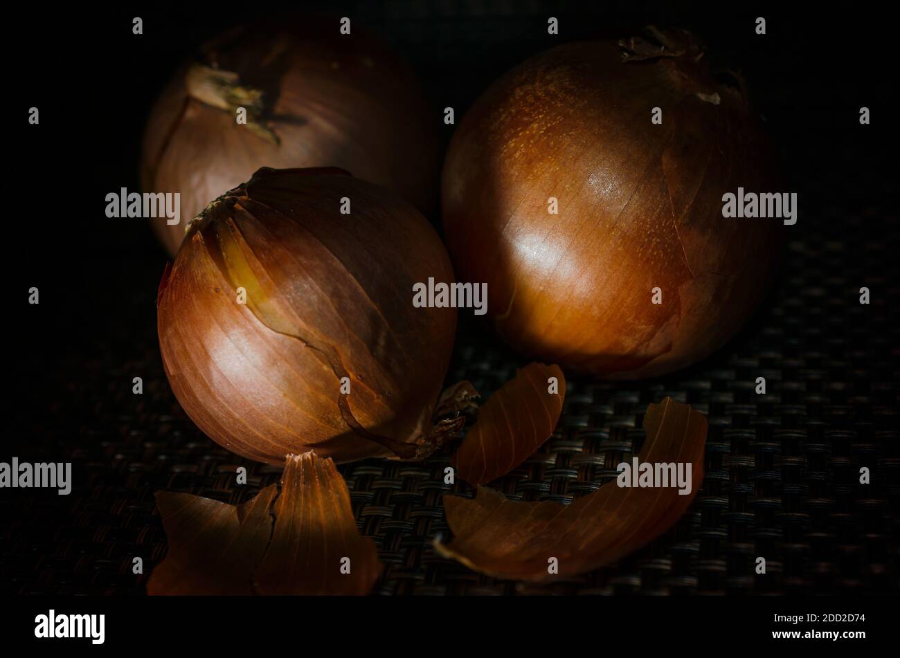 Three yellow onions are pictured unpeeled. Yellow onions are a variety of onion with a whitish, yellow inside and yellow, brown or reddish skin. Stock Photo