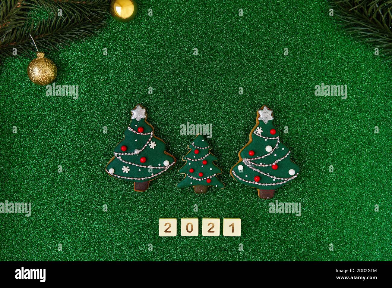 New Year holiday card. On a green isolated background a happy family of christmas trees with a small child written the letters of the numbers 2021 wit Stock Photo