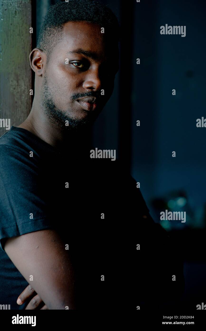 Sad african man standing in dark room. Depression and anxiety disorder