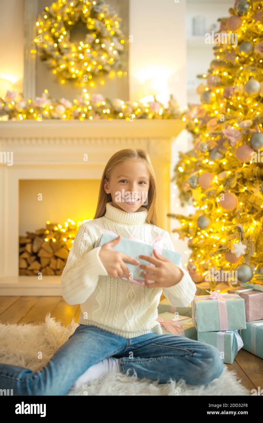 Blonde cute girl looking happy while holding her gift box Stock Photo ...