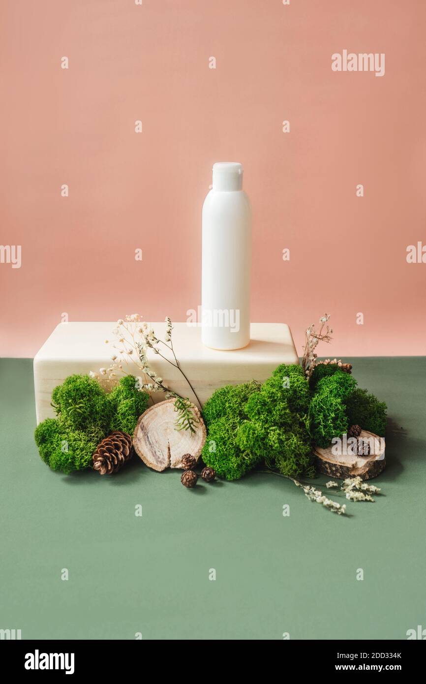 Blank white bottle on wooden brick with green moss. Natural organic cosmetics, alternative medicine, herbal essence, sustainable lifestyle concept. Fr Stock Photo