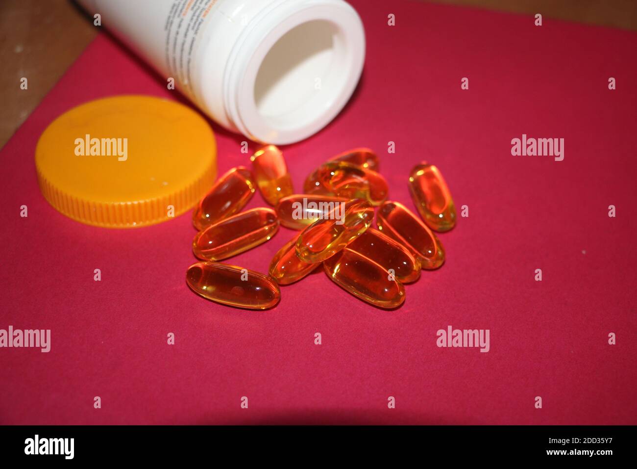 Cod liver oil omega 3 gel capsules in wooden spoon on red background Stock  Photo - Alamy