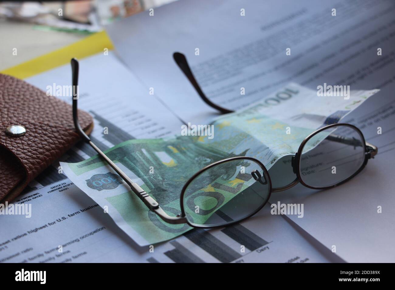 Brown leather wallet, 100 Euro banknote, glasses and financial report. Finance profit and loss analysis business concept Stock Photo