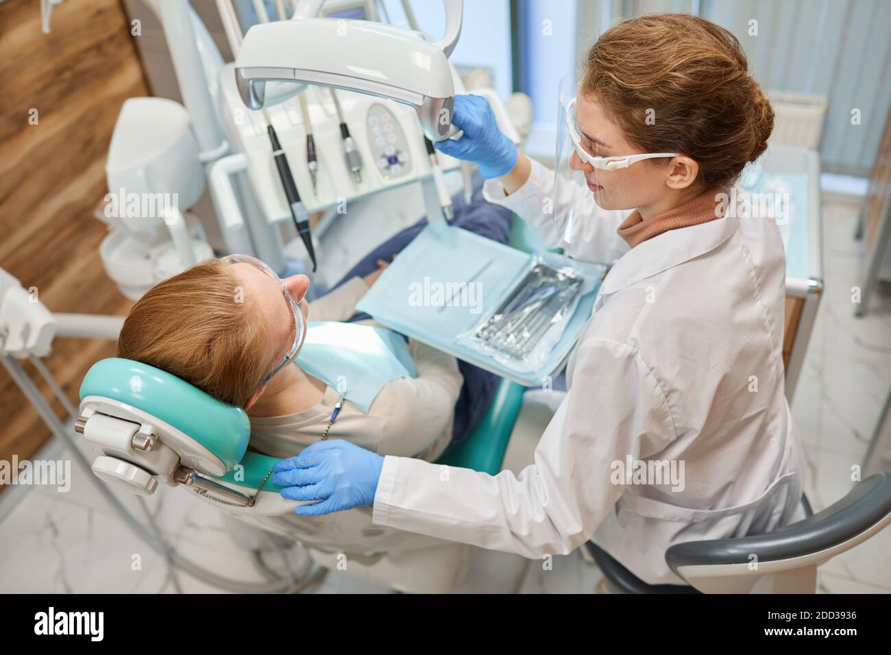 Dentist using medical instruments during dental procedure with patient