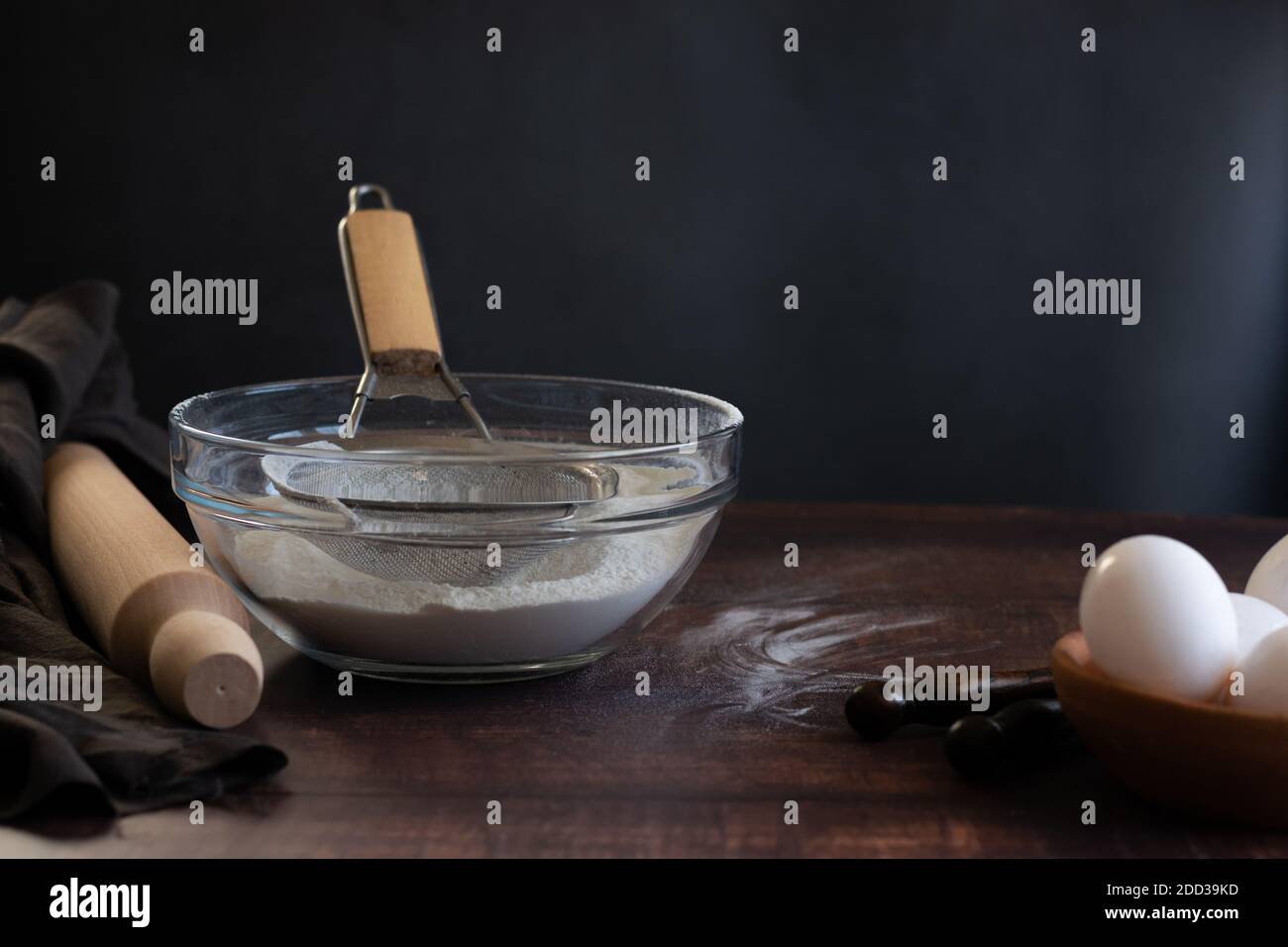 Bakery items - flour and eggs on dark background, healthy basic baking ingredients. Space for text Stock Photo