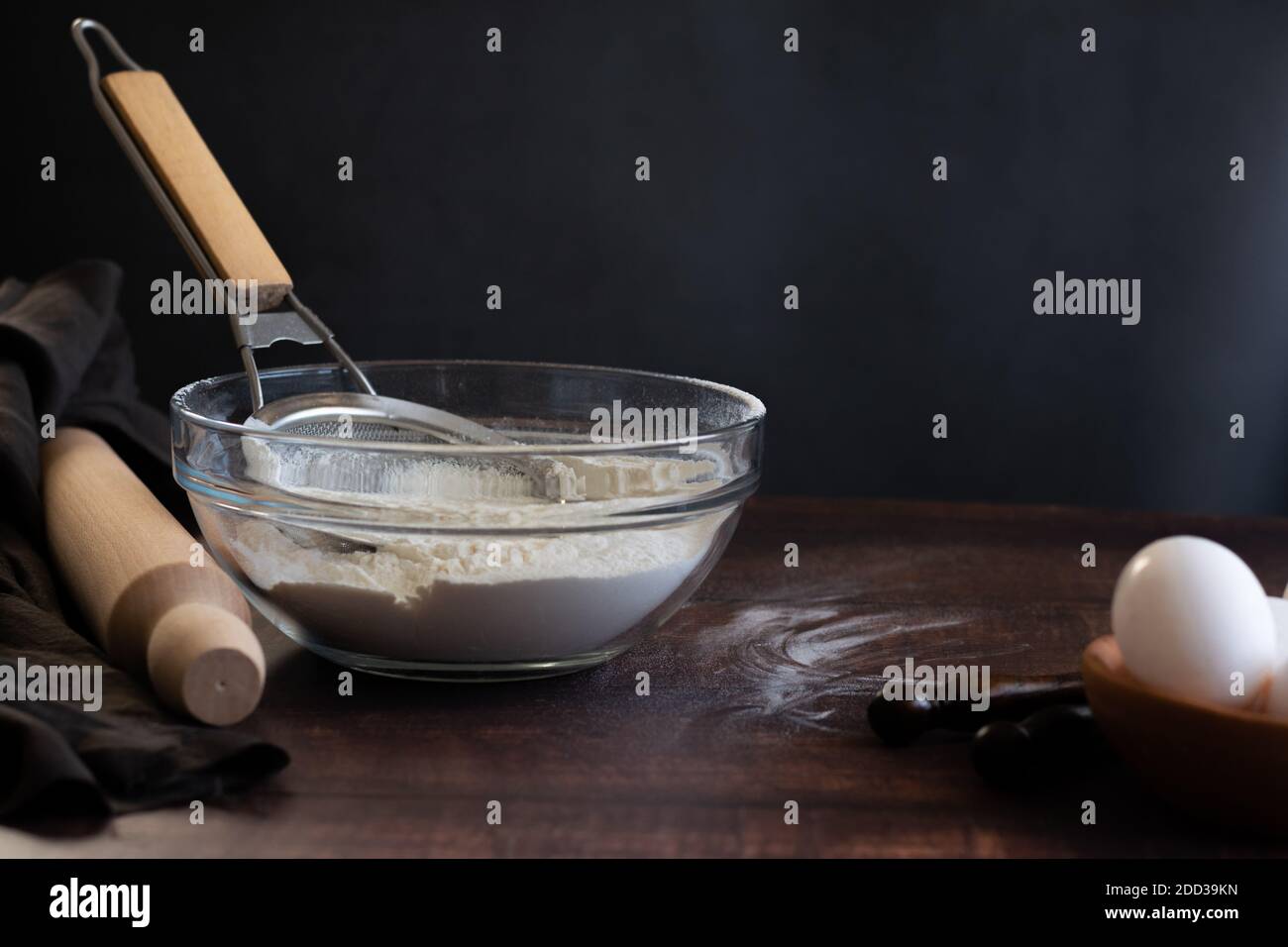 Bakery items - flour and eggs on dark background, healthy basic baking ingredients. Space for text Stock Photo