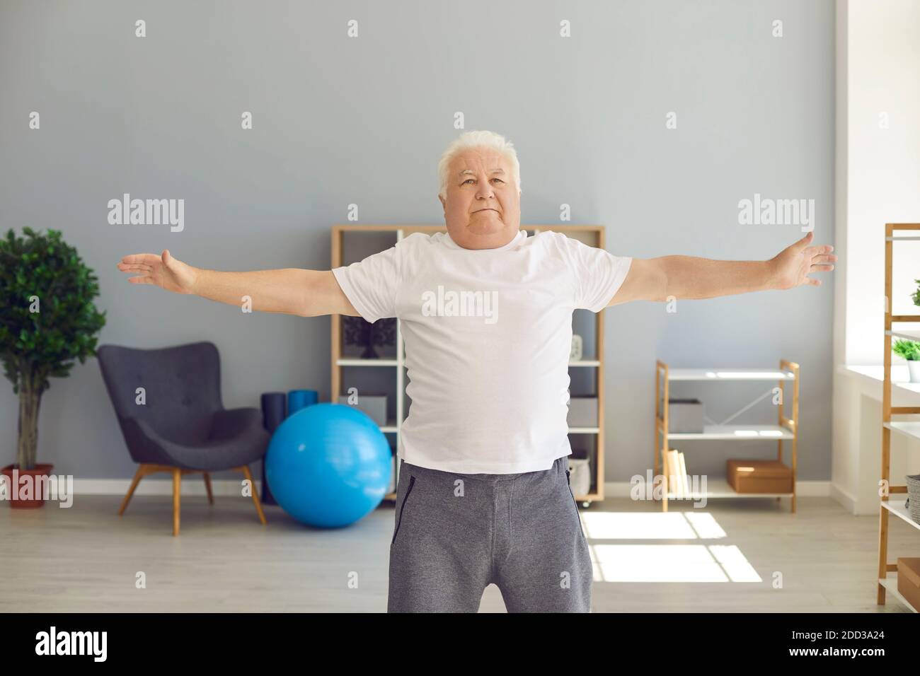 Mature gray haired man doing exercises or light fitness workout at home or rehabilitation clinic Stock Photo
