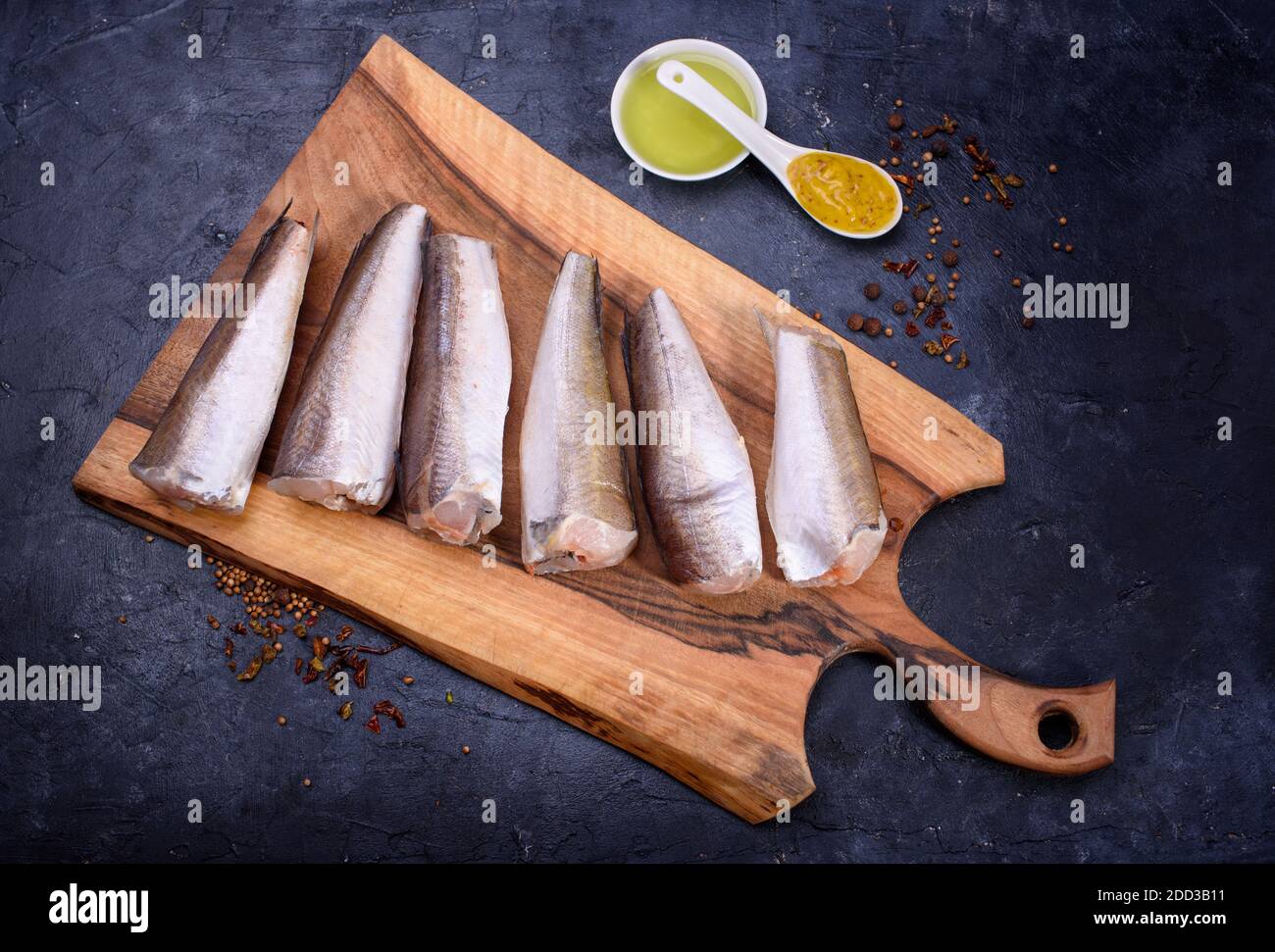 Fresh fish notation on a wooden board, with olive oil, sauce, spices, fresh lettuce leaves. Useful food.Flat lay Stock Photo