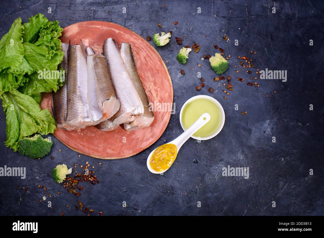 Fresh fish notation on a wooden board, with olive oil, sauce, spices, fresh lettuce leaves. Useful food.Flat lay Stock Photo