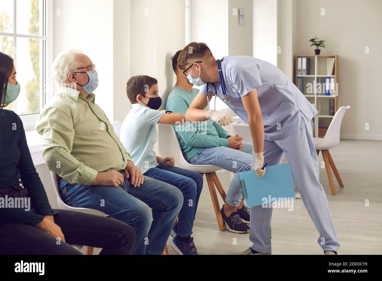 Diverse people wearing medical face masks waiting in line to get flu or Covid-19 shot Stock Photo