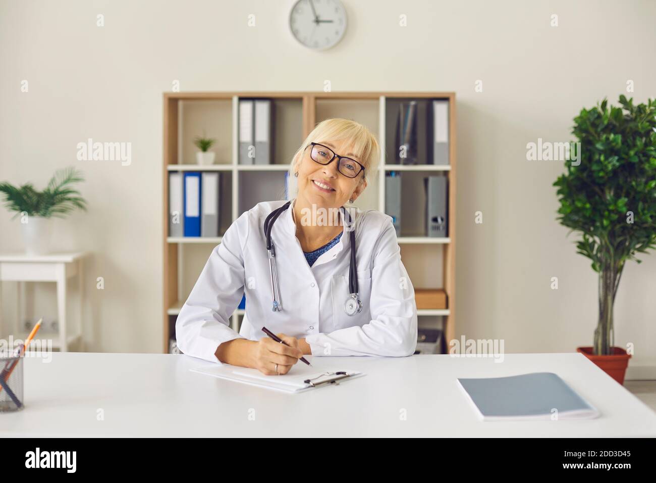Female family doctor sits in front of the camera and gives an online consultation to her patient. Stock Photo