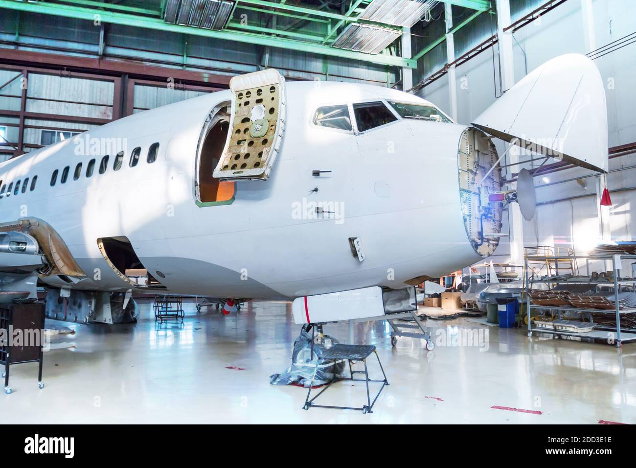 White passenger airplane under maintenance in the hangar. Checking mechanical systems for flight operations. The aircraft has opened weather radar Stock Photo