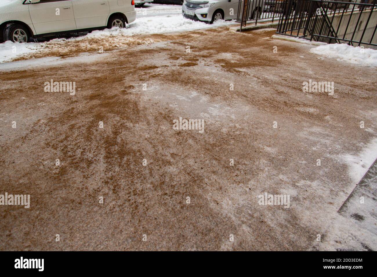 Sand is sprinkled over icy asphalt, snow-covered concrete tiles for people to resist slipping. Stock Photo