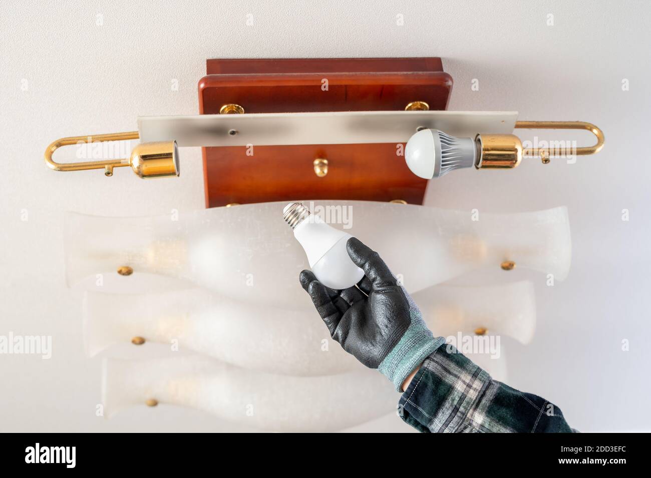 Hand of a gloved man replacing an LED bulb Stock Photo - Alamy