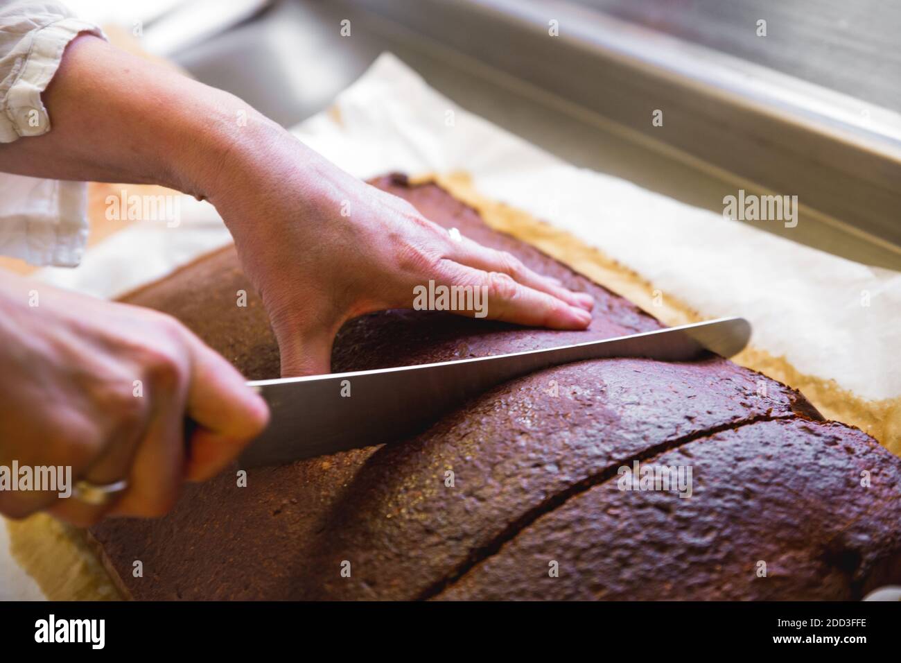 Hands cutting fresh home made dark whole wheat bread Stock Photo - Alamy