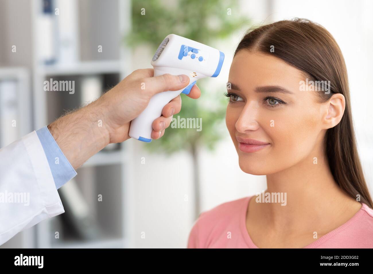 Doctor checking temperature of woman using infrared thermometer Stock