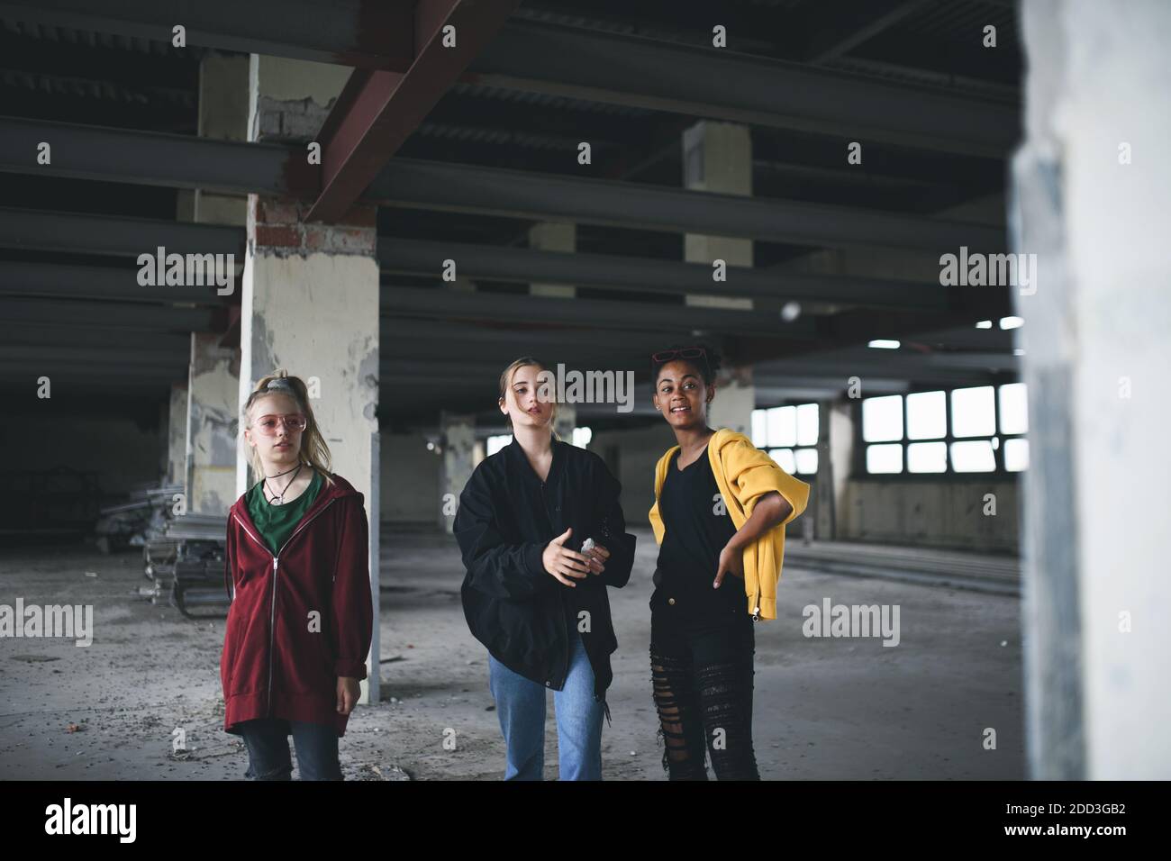 Group of teenagers girl gang indoors in abandoned building, hanging out. Stock Photo