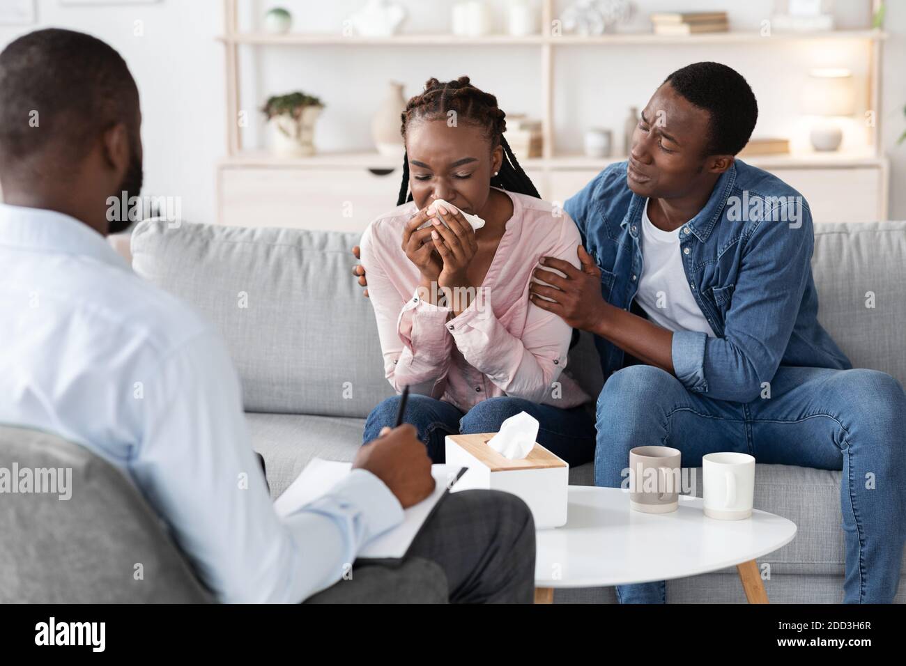 Young black woman crying at meeting with family counselor, husband comforting her Stock Photo