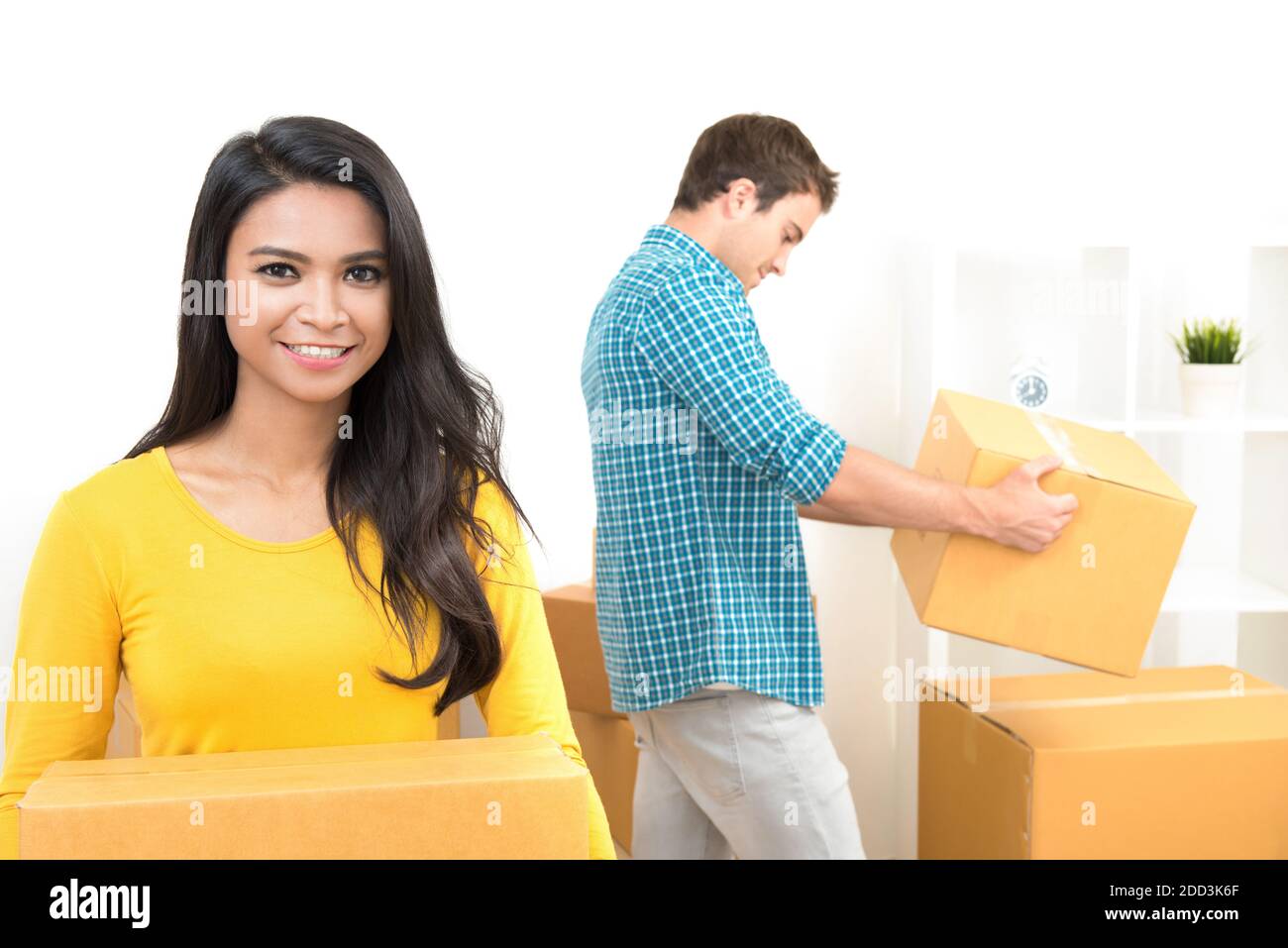 Young interracial couple carrying boxes moving to new house Stock Photo