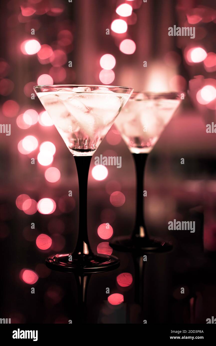 A pair of glasses of fresh cocktail with ice on dark bokeh background. Night date, celebration or party background. Stock Photo