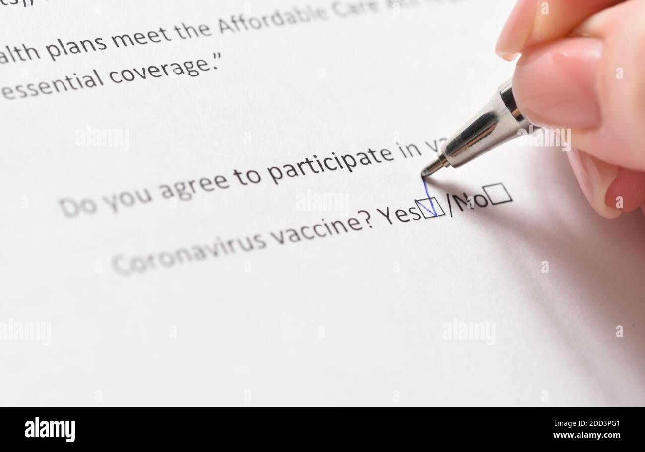 The woman agrees to be vaccinated against coronavirus and ticks the questionnaire. Stock Photo