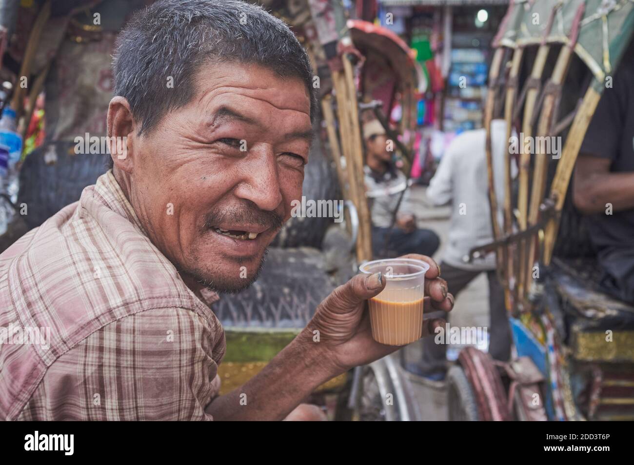 A cheerful cycle rickshaw driver in Kathmandu, Nepal, having milk tea ...