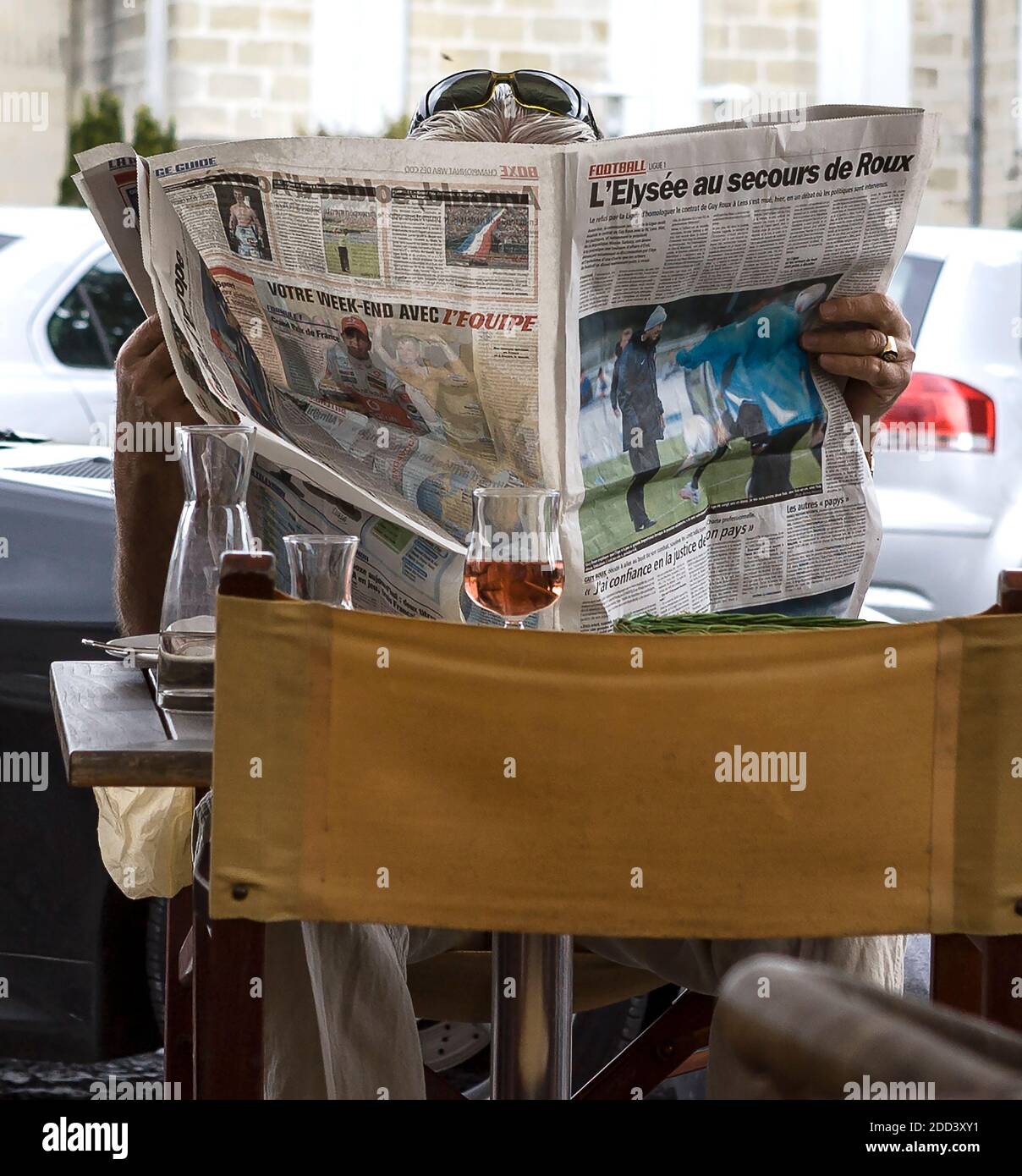 A man at lunch at an outdoor restaurant in Libourne, France, reads his newspaper, the sports daily L'Equipe.. Stock Photo