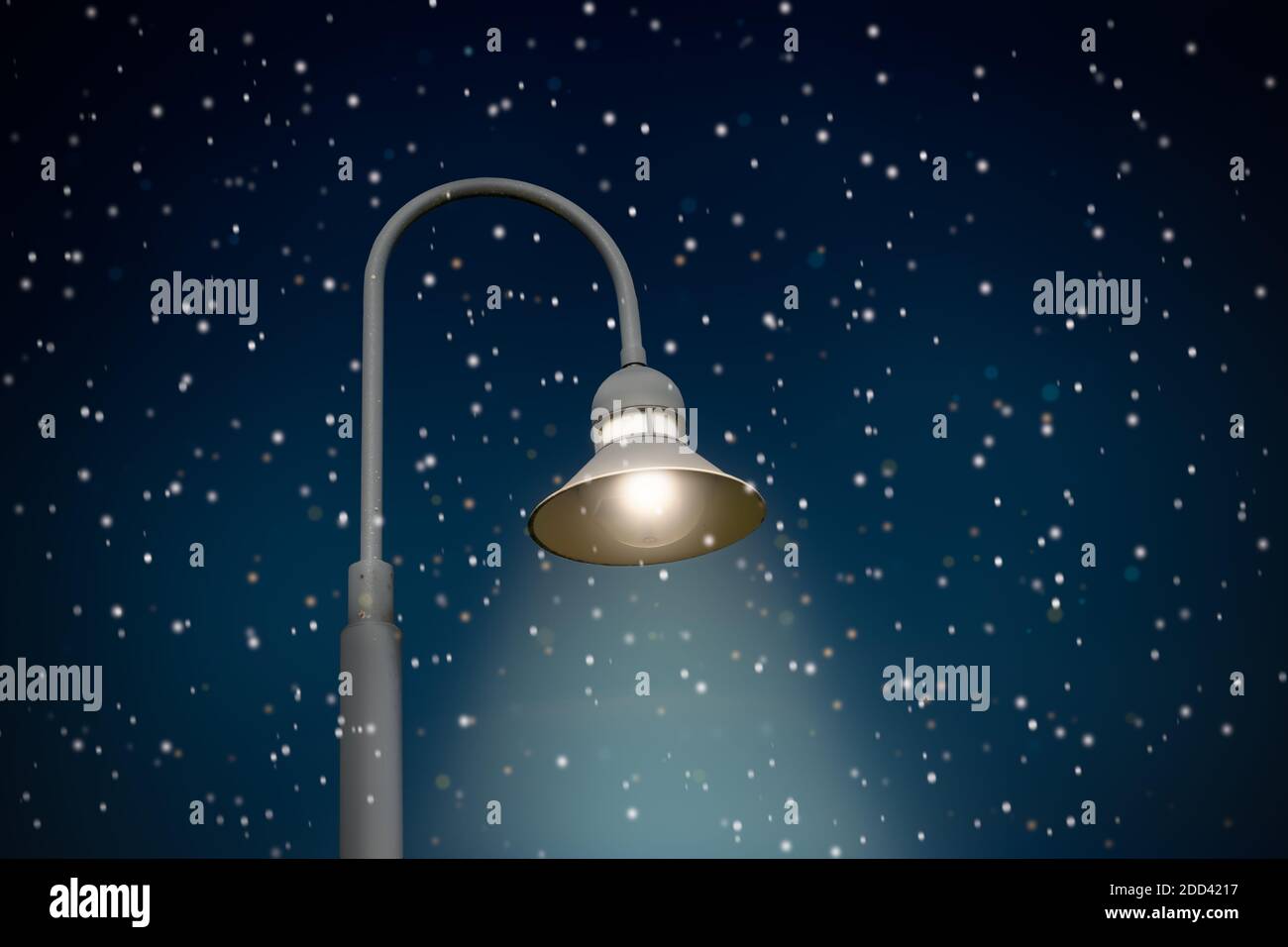 Illuminated street lamp on dark sky with snowflakes. Stock Photo