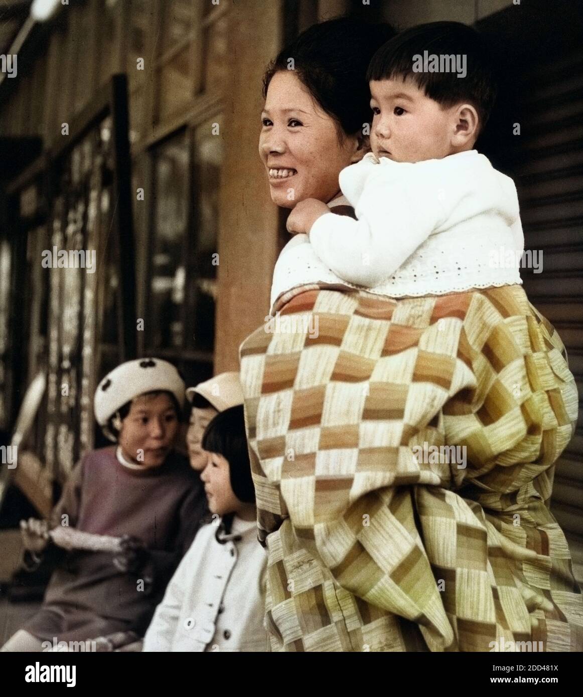 Eine Mutter trägt ihr Kind durch die Straßen von Kyoto, Japan 1960er Jahre. A mother carrying her baby through the streets of Kyoto, Japan 1960s. Stock Photo