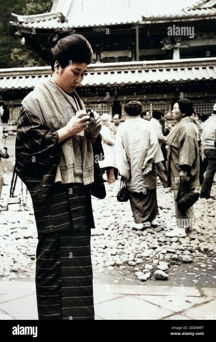 Eine Frau mit einem Fotoapparat im Hof eines Tempels in Japan, 1960er Jahre. A woman taking photos at a courtyard of a temple in Japan, 1960s. Stock Photo