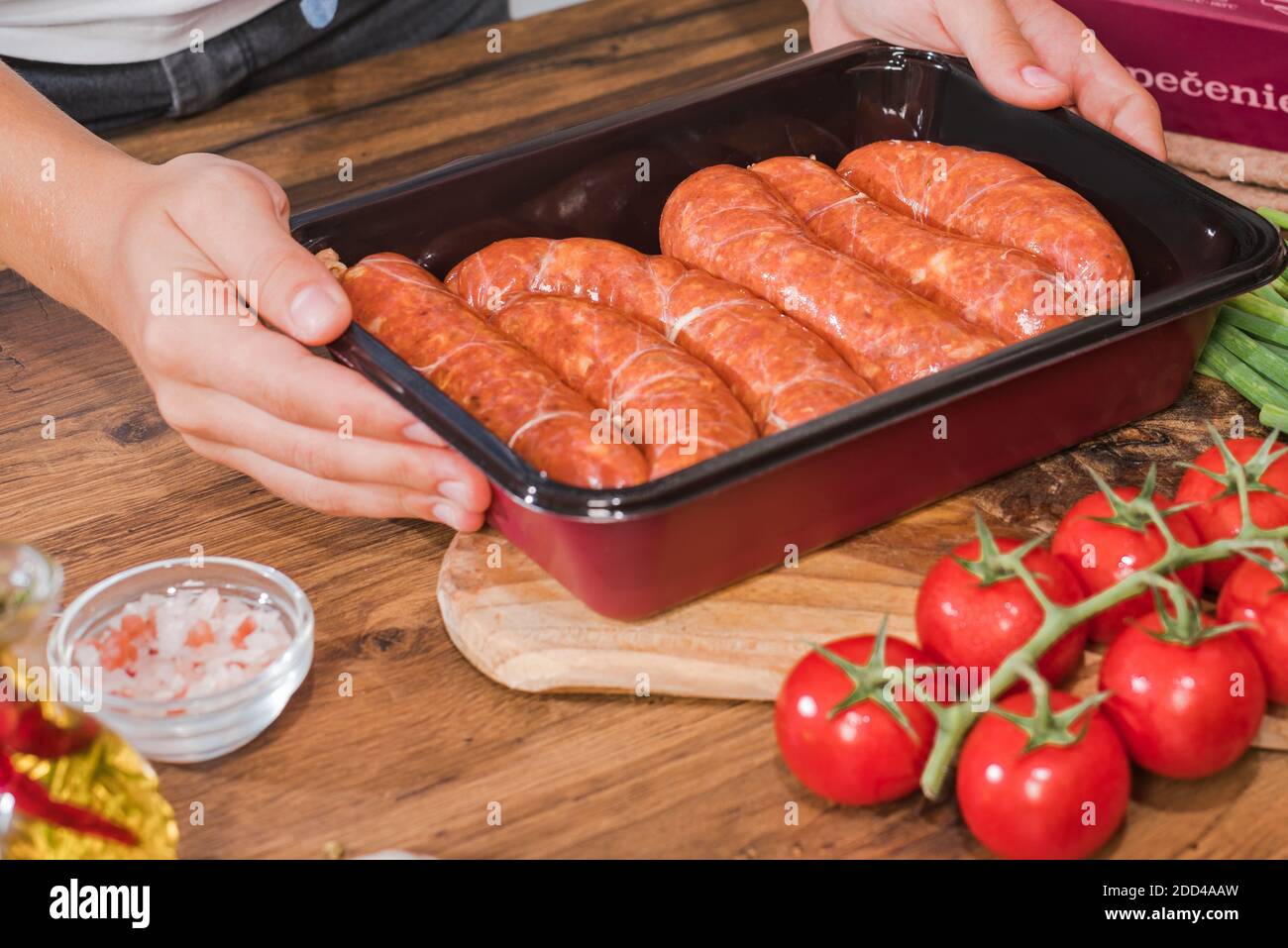 Grilled sausages.Girl prepares grilled sausages in a frying pan in the