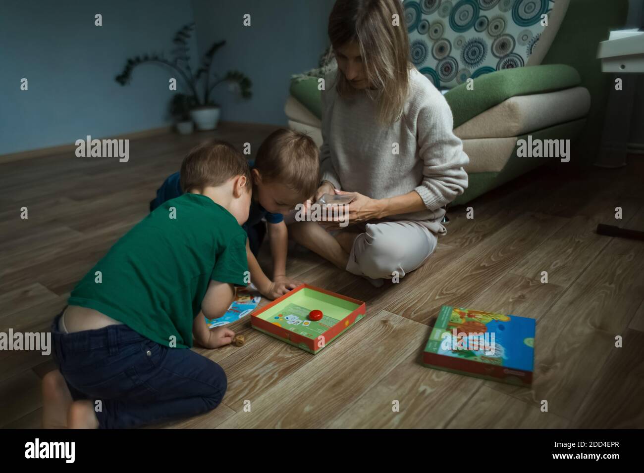 Mother with children playing a board game on the floor. Stock Photo