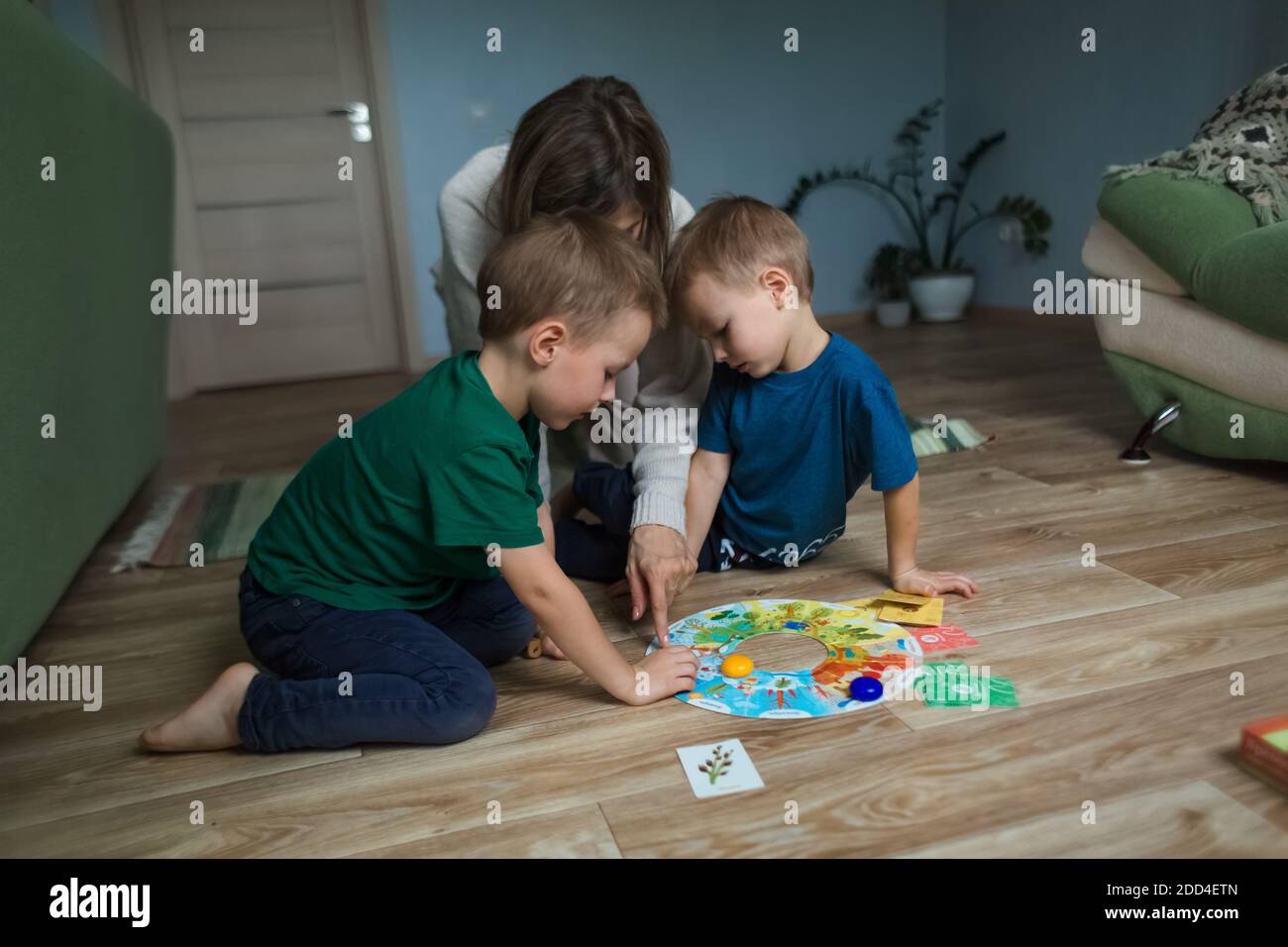 Mother with children playing a board game on the floor. Stock Photo
